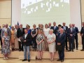 Szerokie zdjęcie, grupa osób stoi na podeście w sali kameralnej Filharmonii w Kielcach. Beneficjenci środków unijnych pozują do pamiątkowego zdjęcia